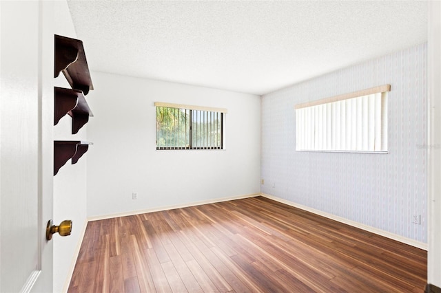 unfurnished room with hardwood / wood-style floors and a textured ceiling