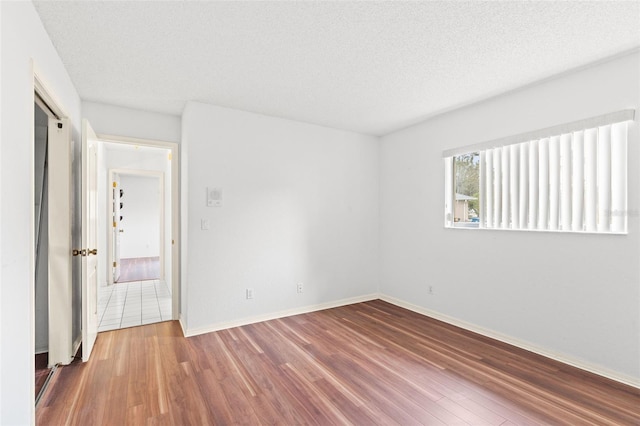 unfurnished room with hardwood / wood-style flooring and a textured ceiling