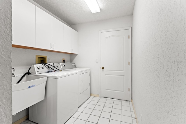 washroom featuring light tile patterned floors, cabinets, a textured ceiling, and washer and clothes dryer