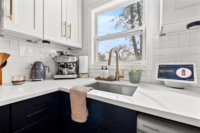 kitchen with dishwashing machine, sink, backsplash, and white cabinets