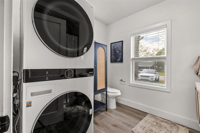 washroom with stacked washer and dryer and light hardwood / wood-style floors