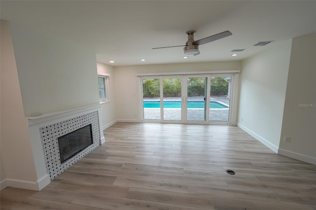 unfurnished living room featuring ceiling fan, a fireplace, and light hardwood / wood-style flooring