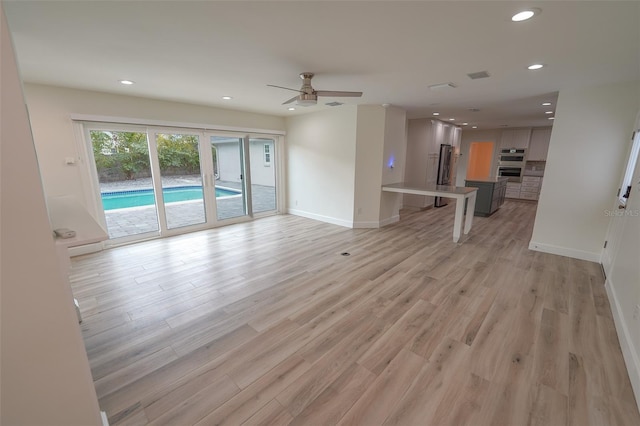 unfurnished living room with ceiling fan and light hardwood / wood-style flooring