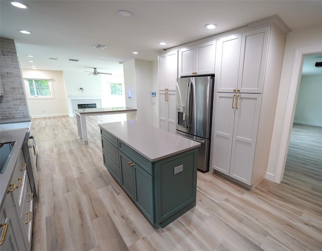 kitchen with stainless steel refrigerator with ice dispenser, a kitchen island, white cabinets, and light hardwood / wood-style flooring