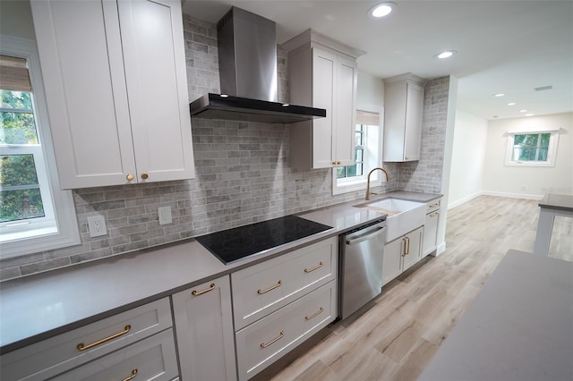 kitchen with white cabinetry, stainless steel dishwasher, light hardwood / wood-style floors, wall chimney range hood, and black electric cooktop