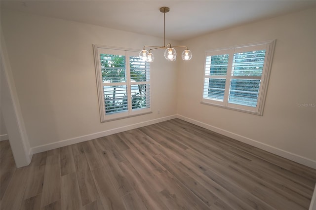 spare room featuring dark hardwood / wood-style floors and a chandelier