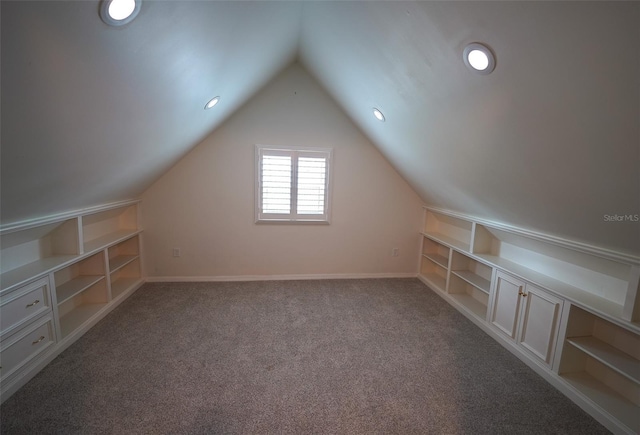 bonus room featuring built in shelves, carpet floors, and vaulted ceiling