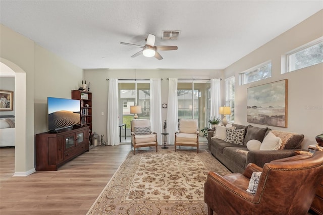 living room with light hardwood / wood-style floors, a textured ceiling, and ceiling fan