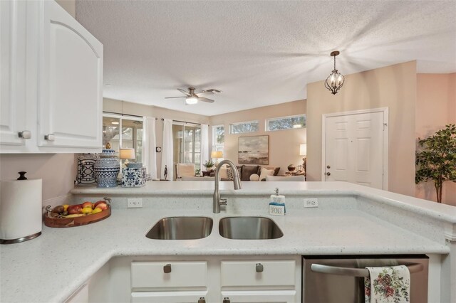 kitchen with pendant lighting, white cabinets, a textured ceiling, sink, and stainless steel dishwasher