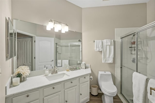 bathroom with a shower with shower door, toilet, and vanity