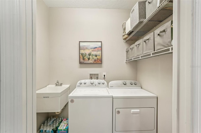 clothes washing area with sink, a textured ceiling, and separate washer and dryer