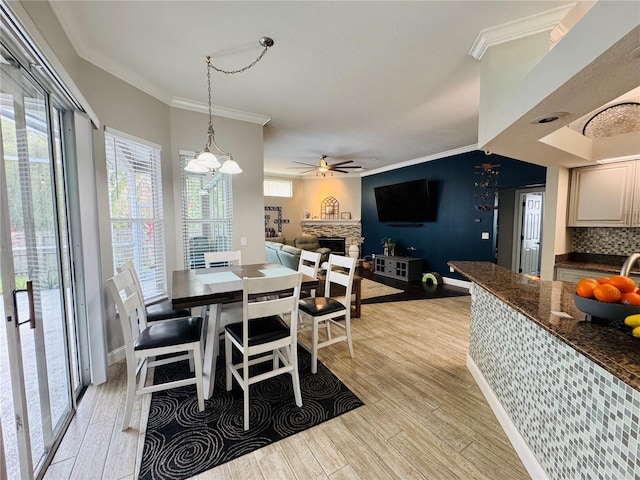 dining space with ornamental molding, light hardwood / wood-style floors, and a fireplace