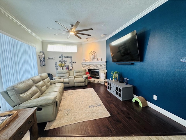 living room featuring a textured ceiling, a fireplace, dark hardwood / wood-style floors, ceiling fan, and crown molding