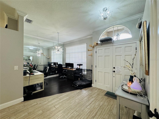 entrance foyer featuring a chandelier, ornamental molding, light hardwood / wood-style floors, and a textured ceiling