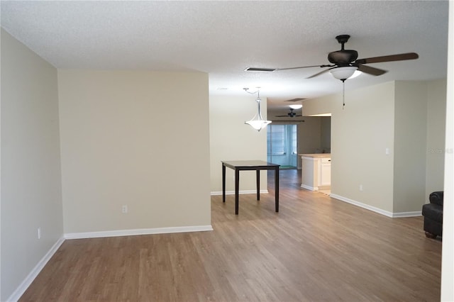 unfurnished room featuring ceiling fan, light hardwood / wood-style floors, and a textured ceiling