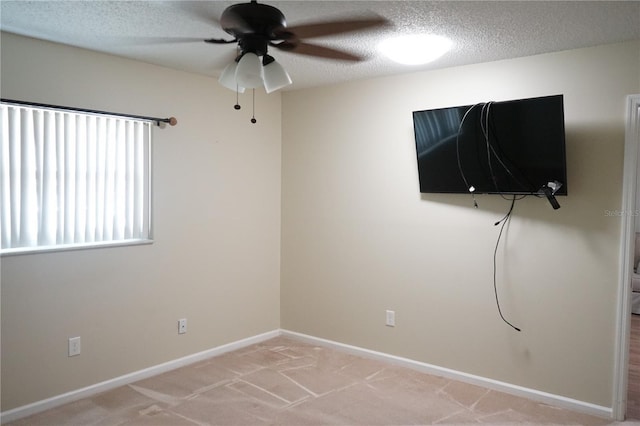 unfurnished room with ceiling fan, light colored carpet, and a textured ceiling