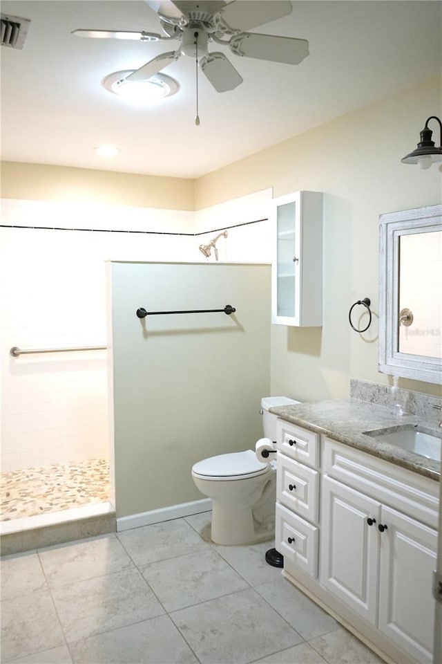 bathroom featuring ceiling fan, vanity, a shower, tile patterned floors, and toilet