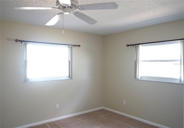 carpeted empty room with ceiling fan, plenty of natural light, and a textured ceiling