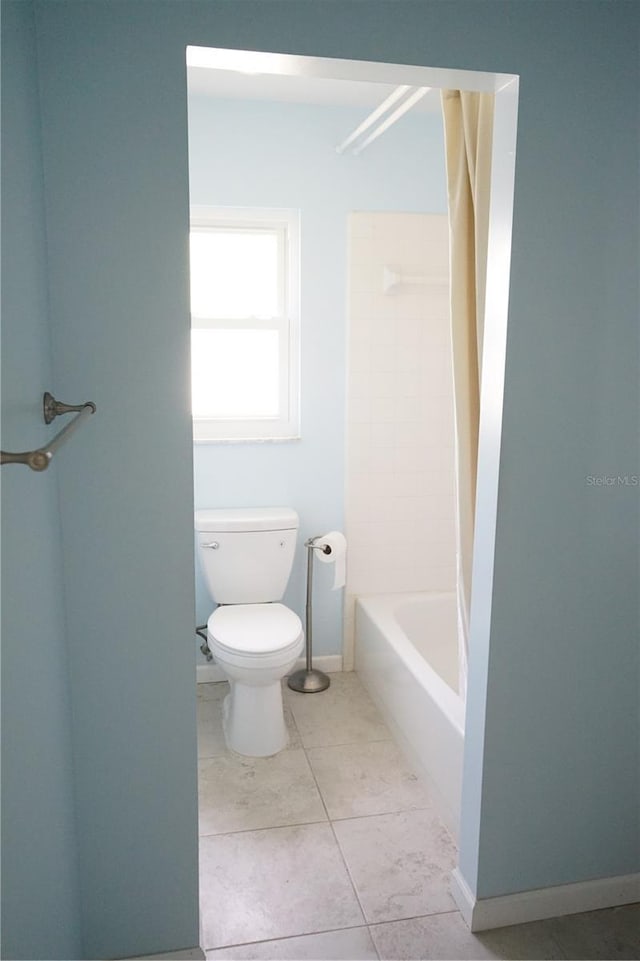 bathroom with tile patterned flooring, shower / washtub combination, and toilet