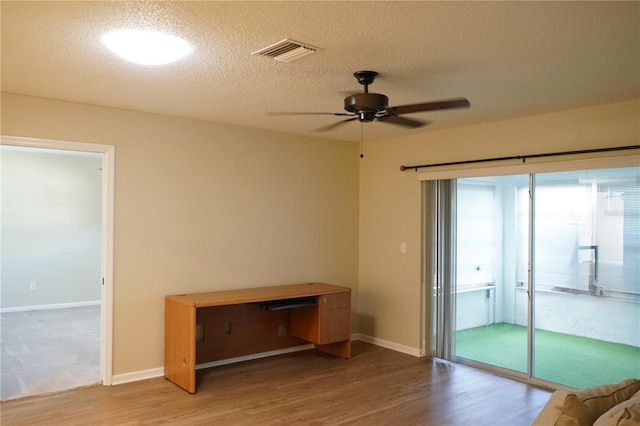 interior space with ceiling fan, light wood-type flooring, and a textured ceiling