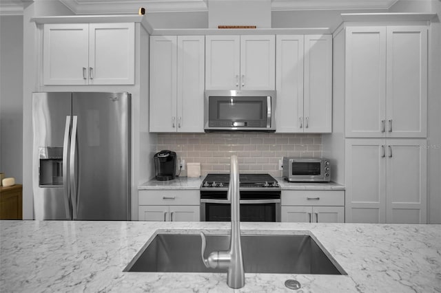 kitchen featuring white cabinetry, decorative backsplash, stainless steel appliances, crown molding, and light stone countertops