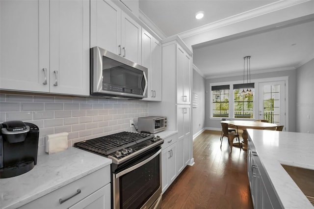 kitchen featuring stainless steel appliances, light stone countertops, hanging light fixtures, and white cabinets