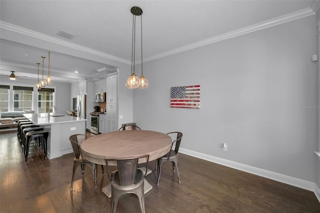 dining room featuring crown molding, sink, dark wood-type flooring, and ceiling fan