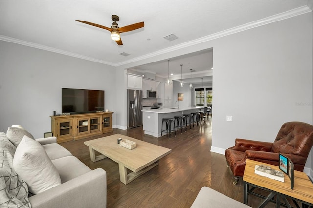 living room with ornamental molding, dark wood-type flooring, sink, and ceiling fan