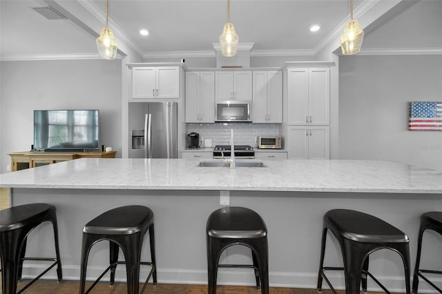 kitchen with pendant lighting, a breakfast bar, appliances with stainless steel finishes, light stone counters, and white cabinets