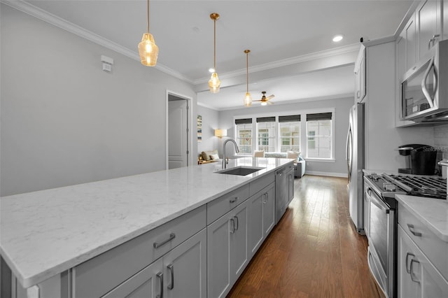 kitchen featuring pendant lighting, sink, stainless steel appliances, ornamental molding, and an island with sink