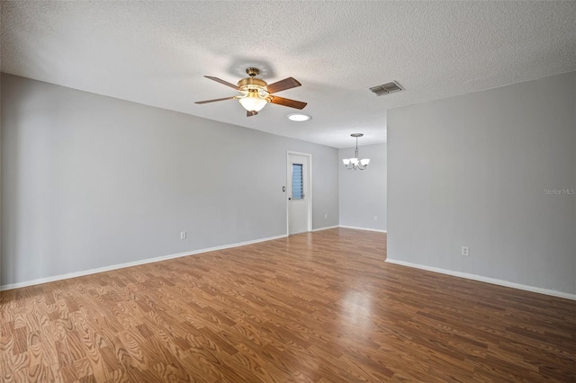 empty room with ceiling fan with notable chandelier, hardwood / wood-style floors, and a textured ceiling