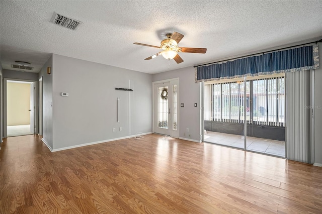 empty room with ceiling fan, a textured ceiling, and light wood-type flooring