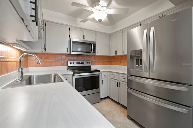 kitchen featuring appliances with stainless steel finishes, tasteful backsplash, light tile patterned floors, sink, and ceiling fan