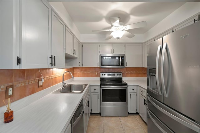 kitchen with appliances with stainless steel finishes, tasteful backsplash, sink, light tile patterned flooring, and ceiling fan