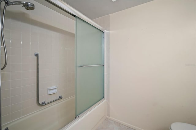 bathroom with tile patterned floors, toilet, and combined bath / shower with glass door