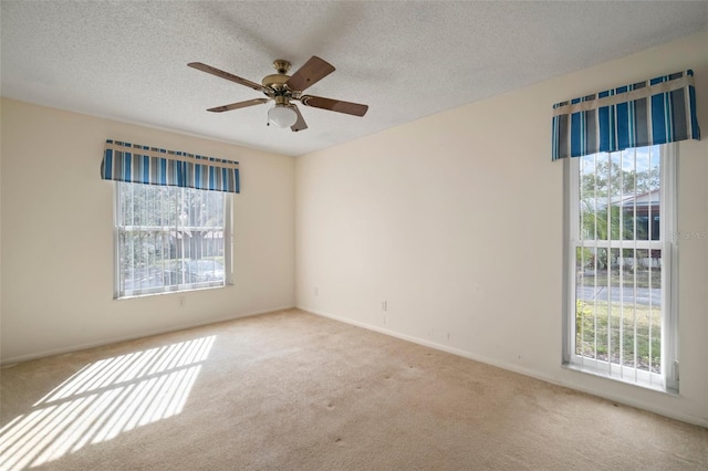 empty room featuring a textured ceiling, light colored carpet, and ceiling fan