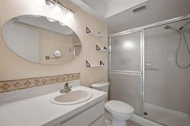 bathroom featuring toilet, a shower with shower door, and vanity