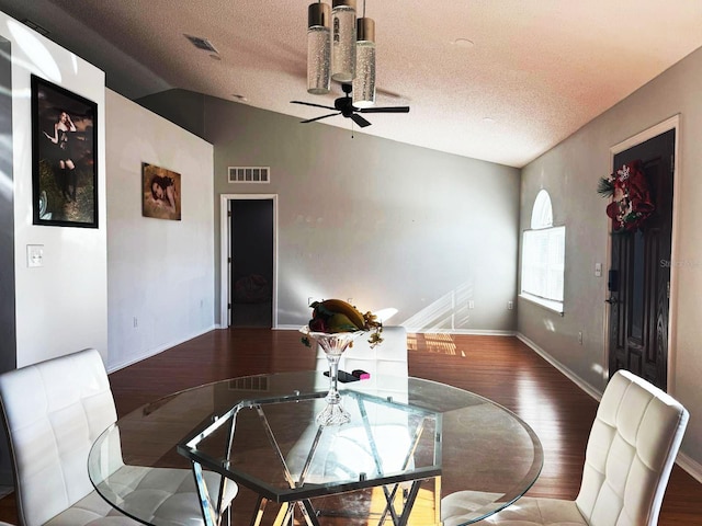 dining space with vaulted ceiling, dark hardwood / wood-style floors, ceiling fan, and a textured ceiling