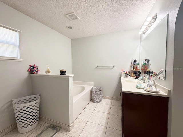 bathroom with tile patterned floors, vanity, a bathtub, and a textured ceiling