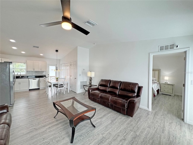 living room featuring ceiling fan, sink, vaulted ceiling, and light hardwood / wood-style flooring