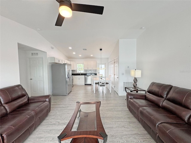 living room featuring light hardwood / wood-style flooring, ceiling fan, and vaulted ceiling