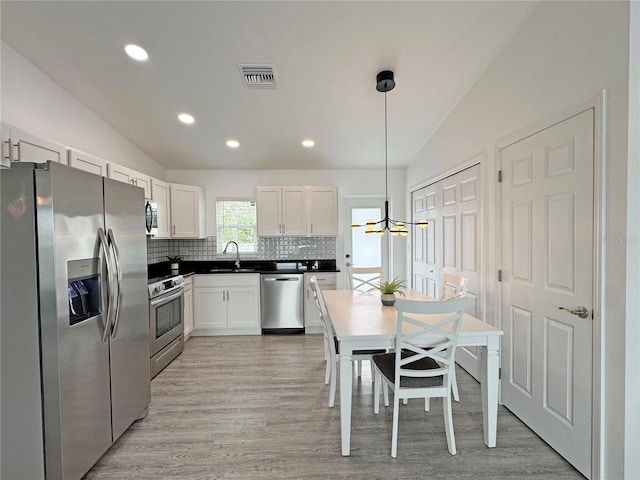 kitchen featuring vaulted ceiling, stainless steel appliances, decorative light fixtures, and sink