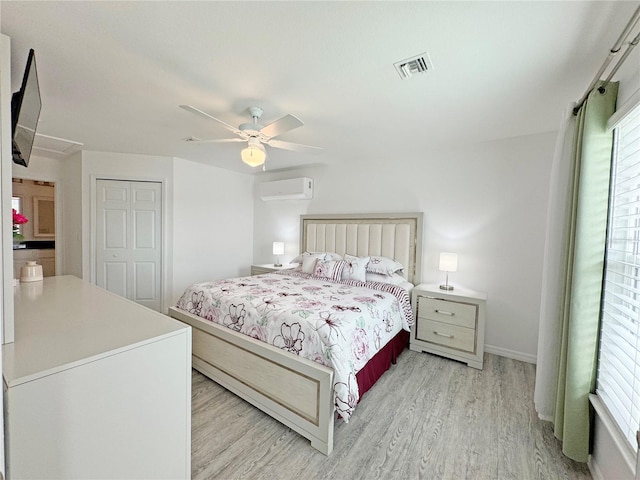 bedroom with light wood-type flooring, a wall mounted air conditioner, ceiling fan, and a closet