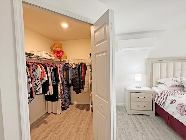 spacious closet with a wall mounted AC and light hardwood / wood-style floors