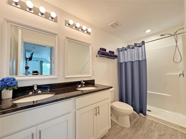 bathroom with wood-type flooring, vanity, walk in shower, toilet, and a textured ceiling