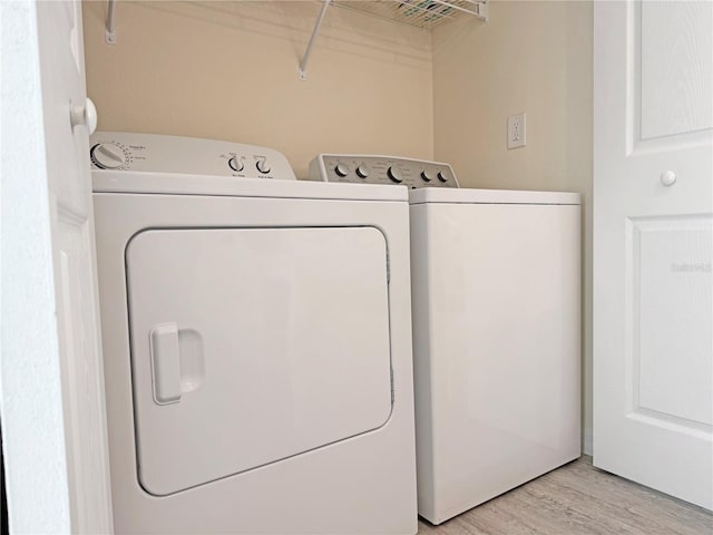 clothes washing area featuring washing machine and dryer and light hardwood / wood-style flooring