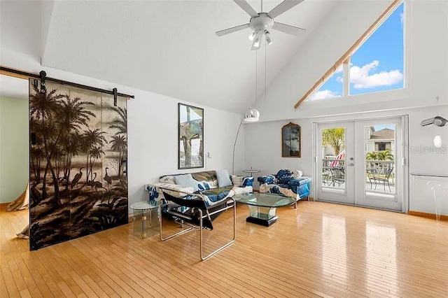 living room featuring a barn door, french doors, ceiling fan, and light wood-type flooring