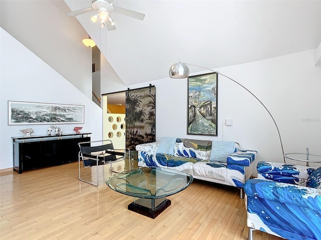 living room featuring wood-type flooring, a barn door, high vaulted ceiling, and ceiling fan