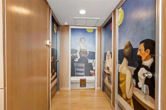 hall with light hardwood / wood-style floors and a textured ceiling