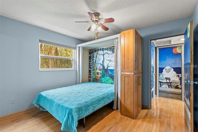 bedroom with ceiling fan, light hardwood / wood-style floors, and a textured ceiling